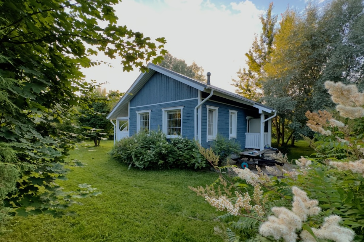 A blue Scandinavian cottage surrounded by a green garden